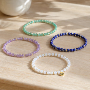 Luck 4 mm crystal bracelet stack - four bracelets on a sunlit table