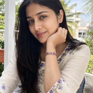 Amethyst bracelet with golden hematite styled on a woman's wrist with an embroidered cream kurta
