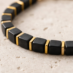 Close-up of black onyx cube beads showing matte black stone and polished golden hematite spacers