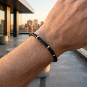 Man wearing black onyx bracelet with silver spacers on a rooftop for grounding and confidence
