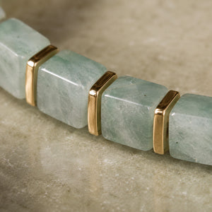Close-up of green aventurine beads showing pale green veined stone and polished golden hematite spacers