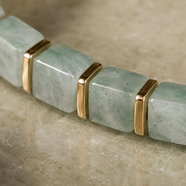 Close-up of green aventurine beads showing pale green veined stone and polished golden hematite spacers