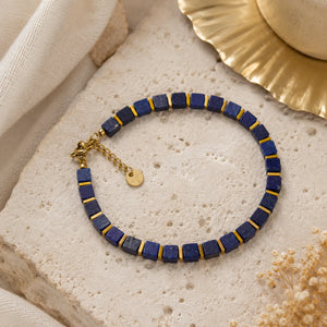 Lapis lazuli bracelet with golden hematite styled on pale travertine with a gold dish and dried flowers