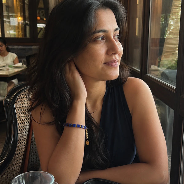 Lapis lazuli bracelet with golden hematite on a woman's wrist at a cafe, styled with a navy top