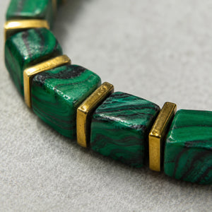 Close-up of malachite beads showing deep green swirl banding and polished gold spacers