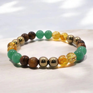Flat-lay close-up of money magnet bracelet beads in gold, green, amber and brown tones