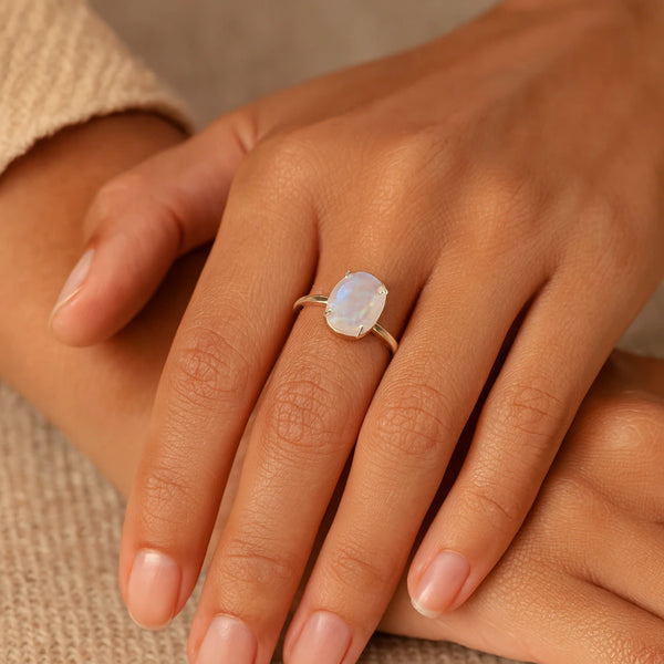 Moonstone glow ring worn on the finger showing blue and white flash, adjustable silver band