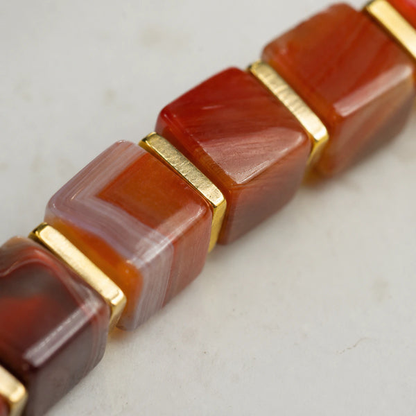 Close-up of red striped agate beads showing warm banding and polished gold spacers