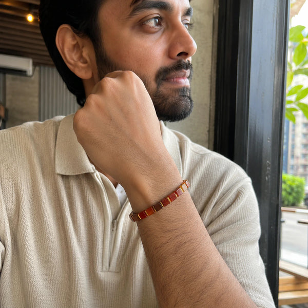 Red striped agate bracelet worn by a man relaxing at a cafe, styled for grounding and warmth