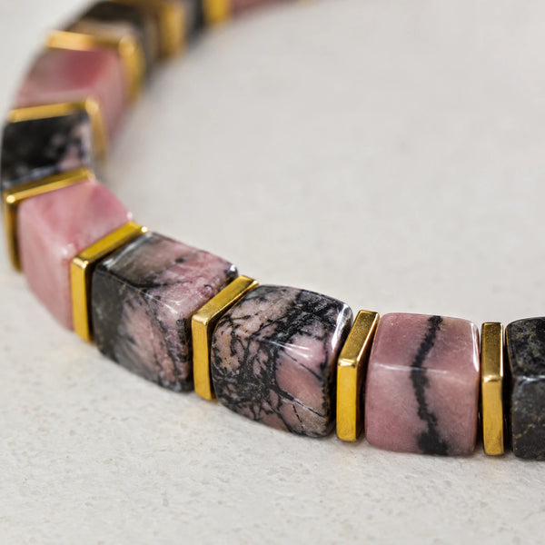 Close-up of pink and black rhodolite garnet beads with veined marbling and gold spacers
