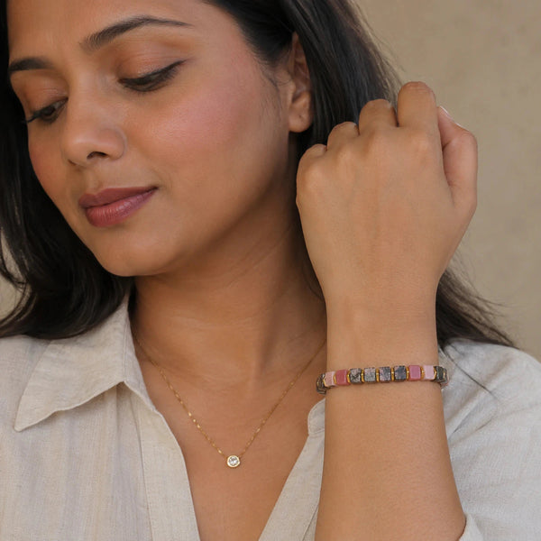 Rhodonite bracelet worn on a woman's wrist with a cream shirt for heart-centered calm