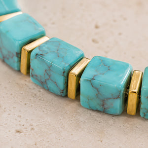 Close-up of turquoise beads showing brown matrix veining and polished gold spacers