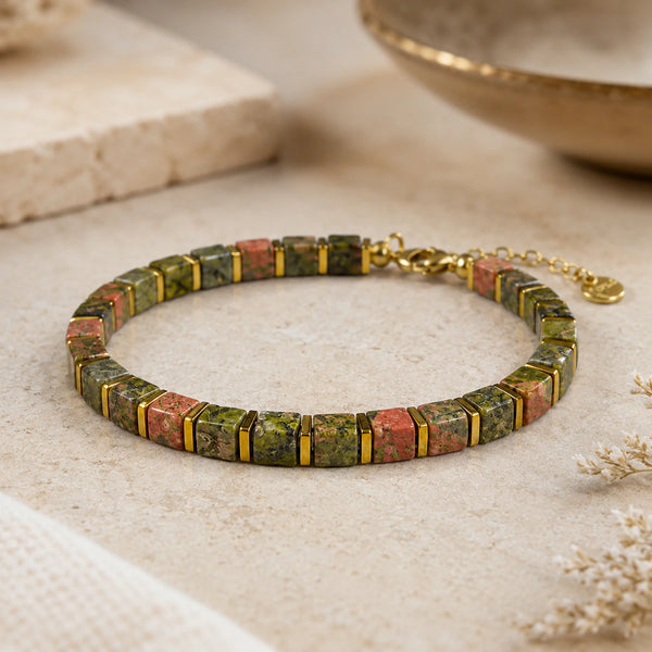 Unakite and golden hematite bracelet laid flat on a cream stone surface for renewal and balance