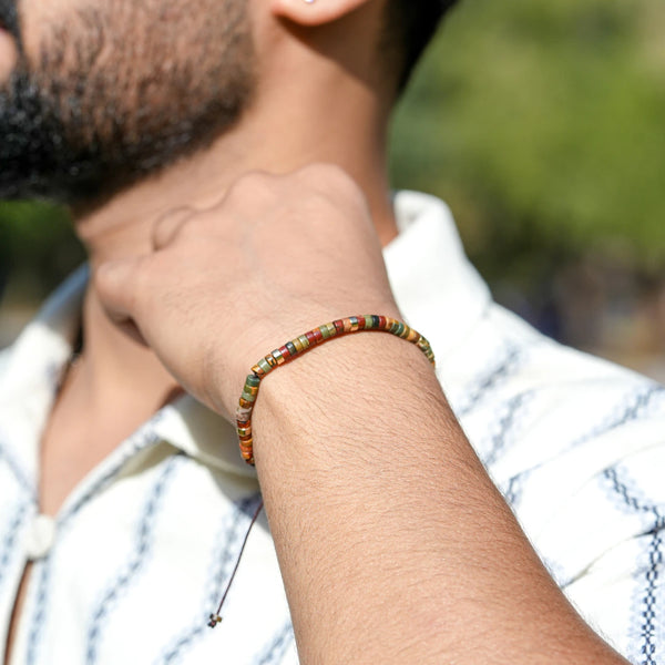 Picasso jasper stone bracelet on a man's wrist outdoors, earthy multicolour heishi beads for grounding
