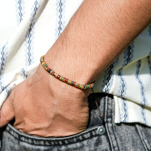 Close wrist shot of picasso jasper bracelet on a man's arm, slim heishi beads with gold accents