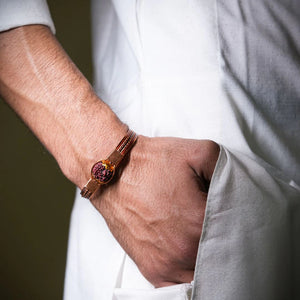 Man in white kurta wearing pure copper rudraksha bracelet on wrist, devotional lifestyle