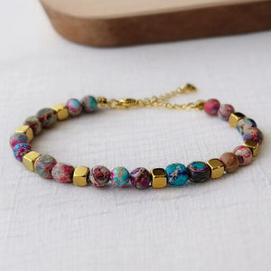 Purple jasper bracelet with gold cube beads for energy cleansing, flat lay on linen - Soultheory