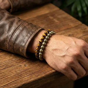 Pyrite and tiger eye bracelets stacked on a wrist in a lifestyle shot for good fortune