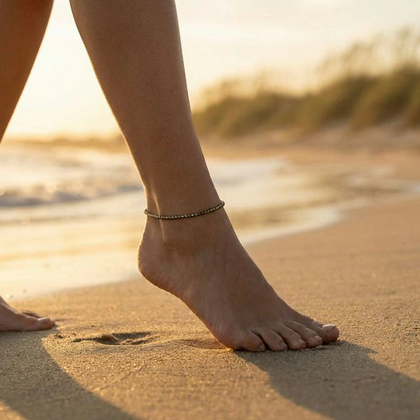 Raw pyrite anklet worn on the ankle on a sandy beach at sunset