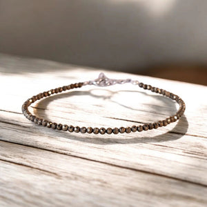 Raw pyrite bead anklet for wealth and good fortune, on a sunlit wooden surface - Soultheory India