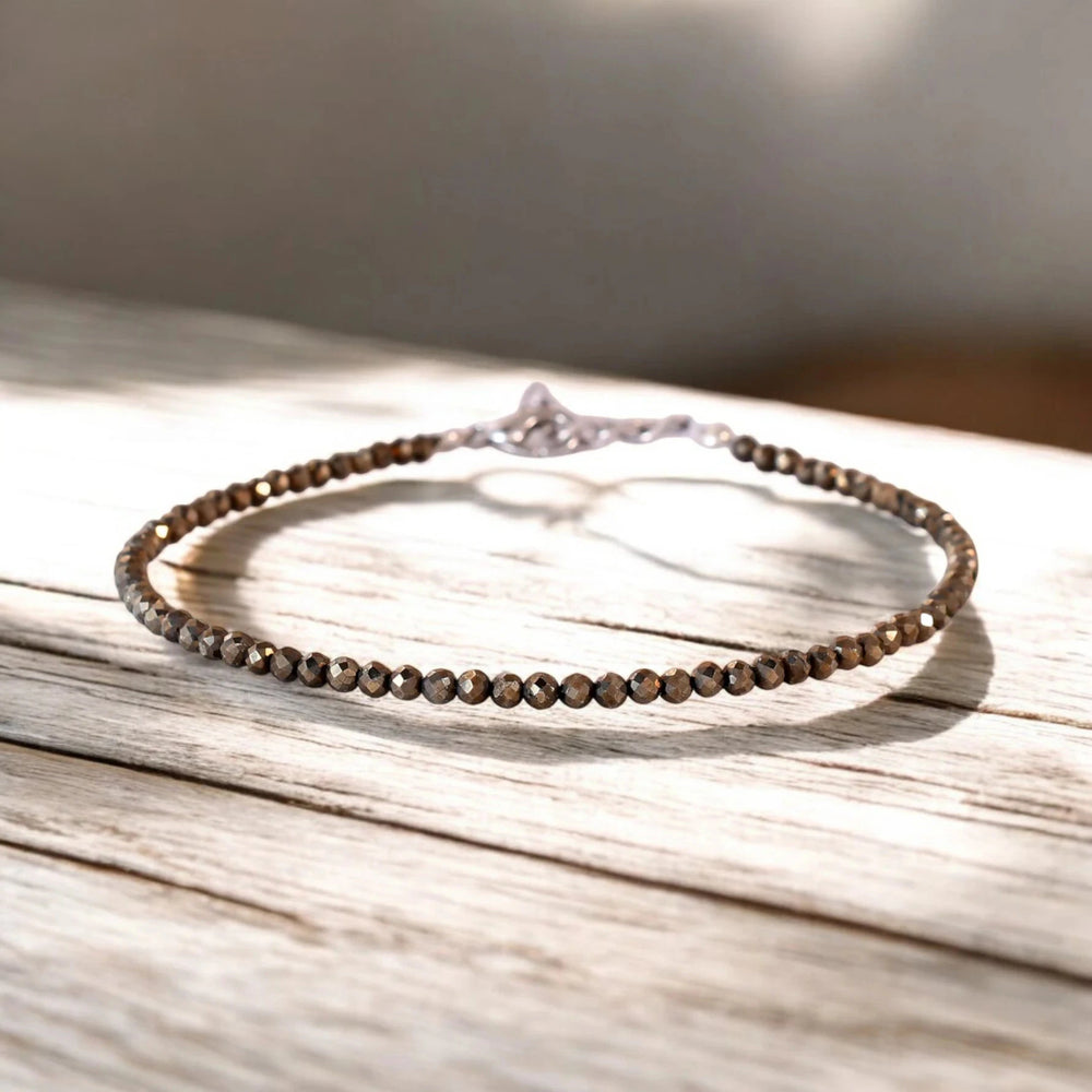 Raw pyrite bead anklet for wealth and good fortune, on a sunlit wooden surface - Soultheory India
