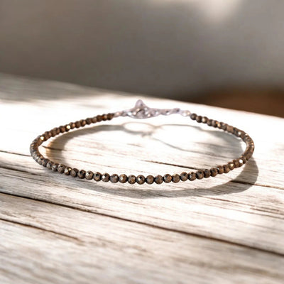 Raw pyrite bead anklet for wealth and good fortune, on a sunlit wooden surface - Soultheory India
