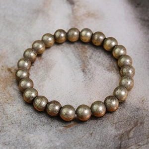 Raw pyrite bead bracelet for wealth and confidence, on a natural stone surface - Soultheory India