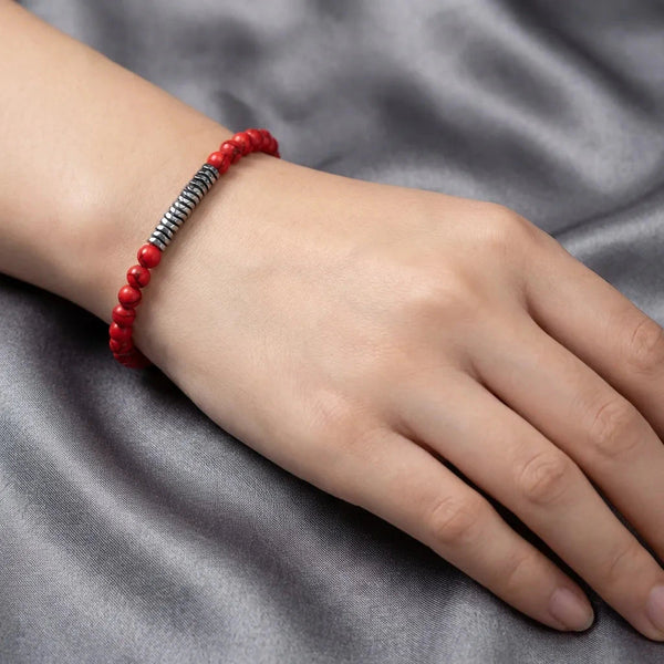 Red turquoise stretch bracelet worn on the wrist against grey satin, polished hematite spacer