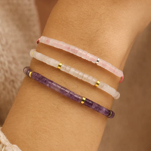 Three manifestation bracelets stacked on the wrist showing rose quartz, clear quartz and amethyst beads