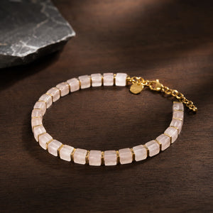 Rose quartz bracelet with golden hematite spacers arranged flat lay on dark wood