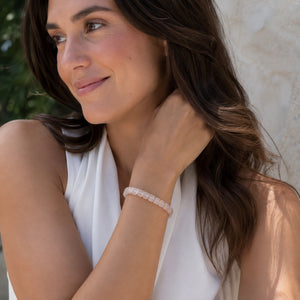 Rose quartz bracelet with golden hematite styled on a woman's wrist for a soft loving look