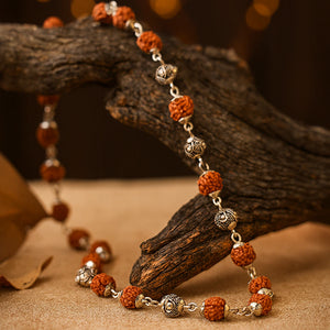 Silver plated rudraksha vel mala draped over rustic wood for daily prayer and japa