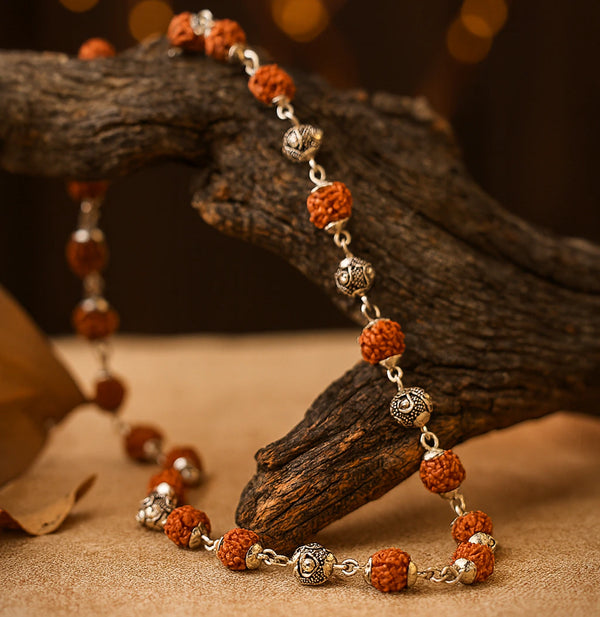 Silver plated rudraksha vel mala draped over rustic wood for daily prayer and japa