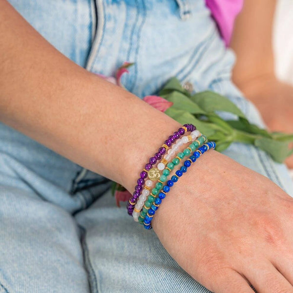 Four fine Soultheory Luck crystal bracelets worn together on a wrist, with Soultheory charm