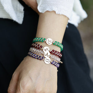 Green Taurus zodiac stone bracelet stacked on a wrist with other zodiac bracelets, gold sign charm on top