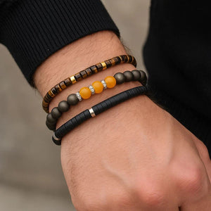 Tiger eye, citrine and black onyx bracelets stacked on a man's wrist for confidence and drive