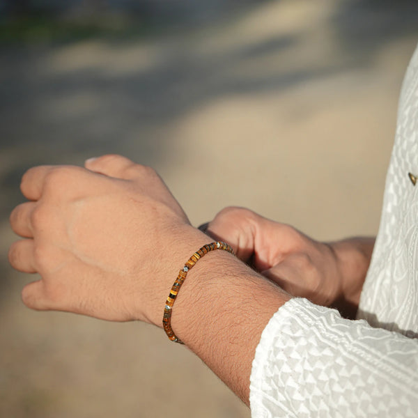Tiger eye bracelet styled on a man's wrist outdoors, golden-brown beads for energy and confidence