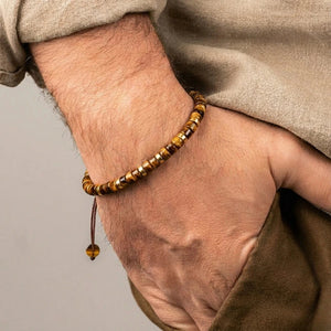 Tiger eye heishi bracelet on a man's wrist with an adjustable cord and a tiger eye drop bead